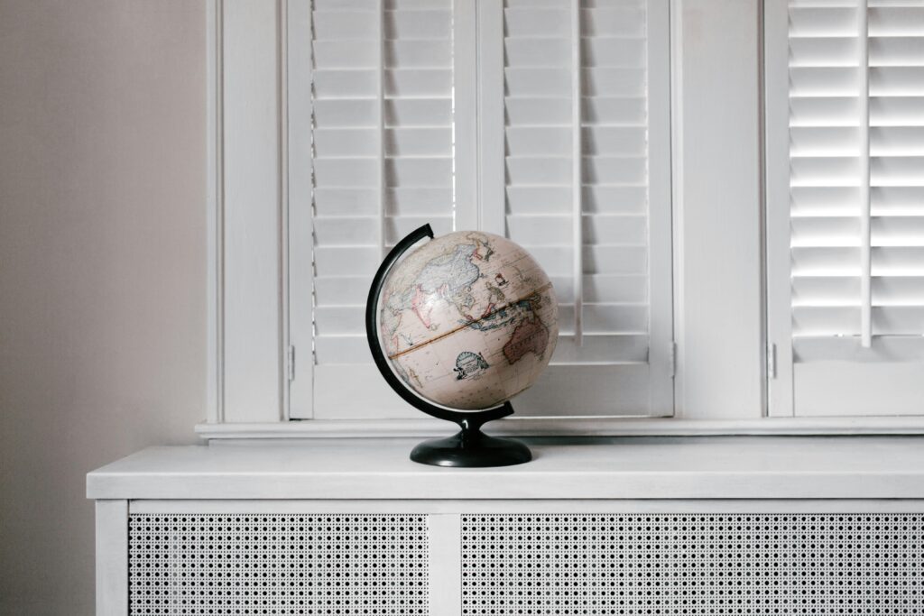 A spinning globe on a table with some cream white shutters in the background