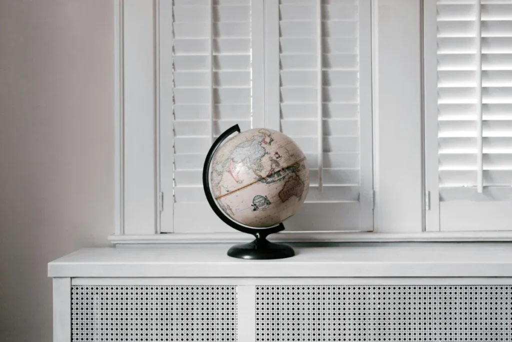 A spinning globe on a table with some cream white shutters in the background