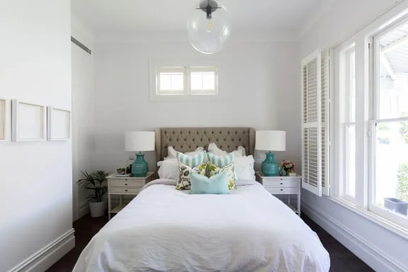 Shot of a feminine country styled master bedroom with white window shutters.